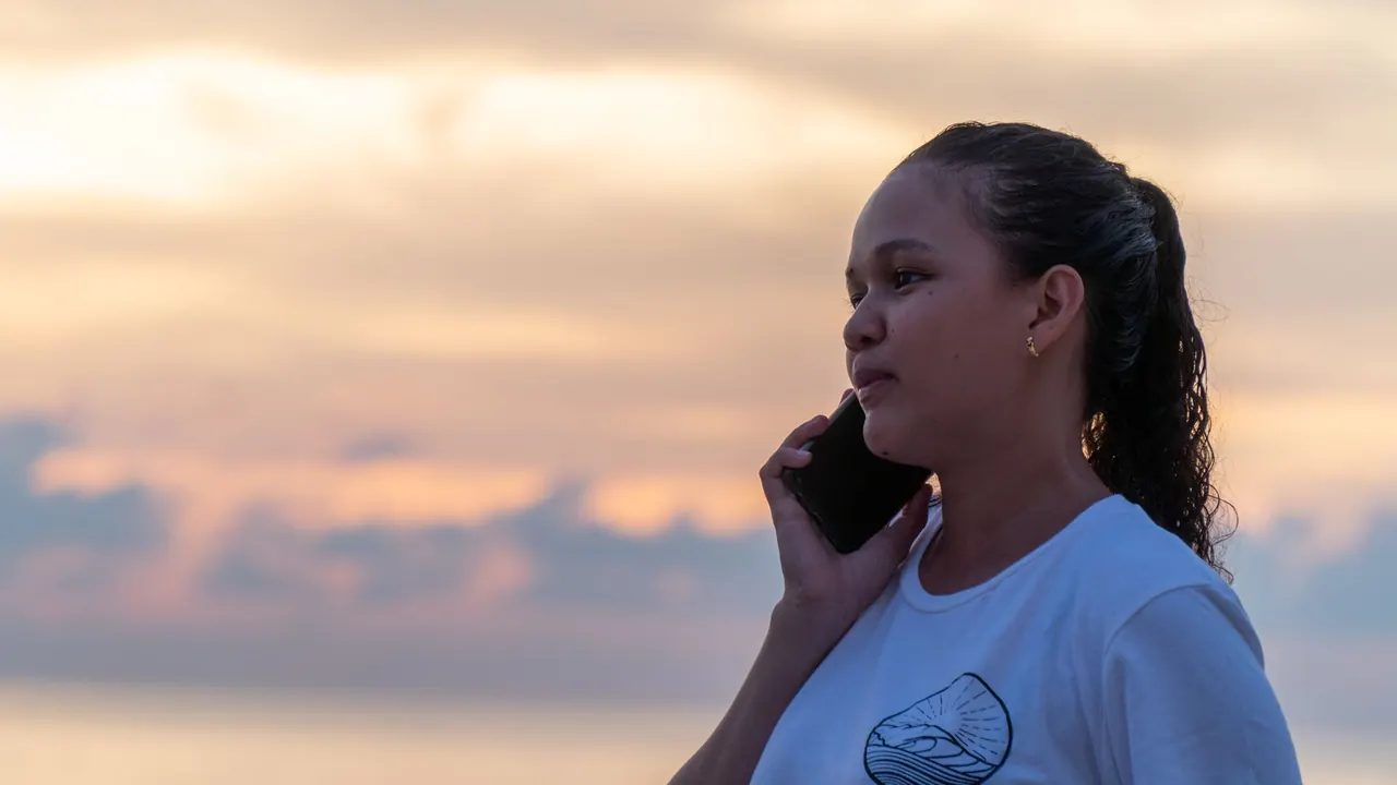 Frau am Strand mit dem Handy bei Sonnenuntergang